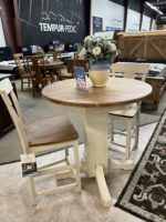 Round wood dining table with two cream-colored chairs on sale.